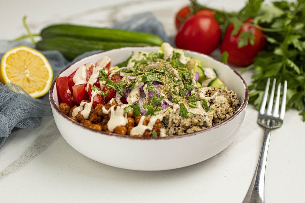 A bowl of food with vegetables and dressing.